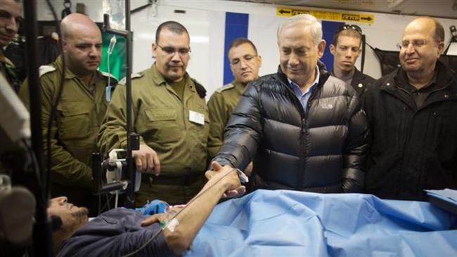 The file photo shows Israeli Prime Minister Benjamin Netanyahu shaking hands with a wounded Takfiri militant at an Israeli field hospital in Syria’s occupied Golan Heights.
