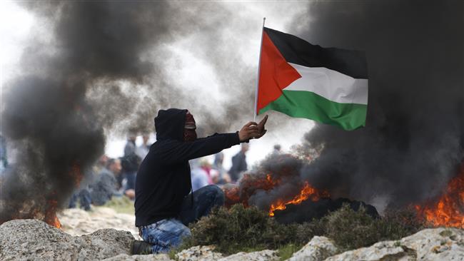 A demonstrator holds a Palestinian flag as Israeli forces clash with Palestinians protesting against a planned new settlement near Mughayyir village close to the West Bank city of Ramallah on March 24, 2017. (Photo by AP)
