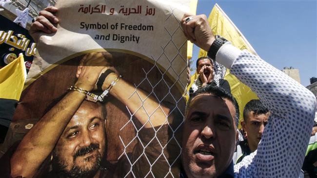 A man holds a photo of prominent Palestinian prisoner Marwan Barghouti calling for his release during a rally supporting those detained in Israeli jails after hundreds of them launched a hunger strike, in the West Bank town of Hebron (al-Khalil) on April 17, 2017. 
