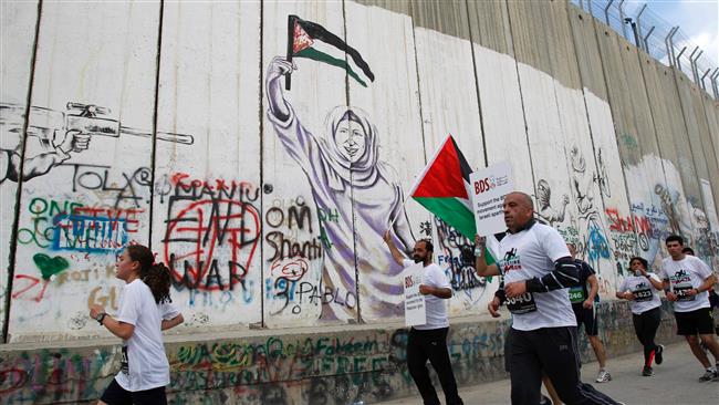 Participants in the 5th Palestine Marathon run along the contentious separation barrier, which divides the West Bank from Jerusalem al-Quds, in Bethlehem on March 31, 2017. (Photo by AFP)
