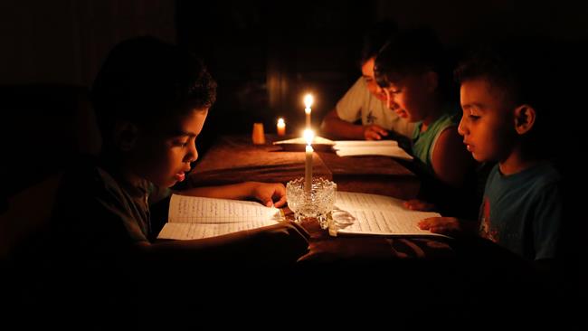 A picture taken on June 13, 2017 shows Palestinian children at home reading books by candle light due to electricity shortages in Gaza City. (By AFP)
