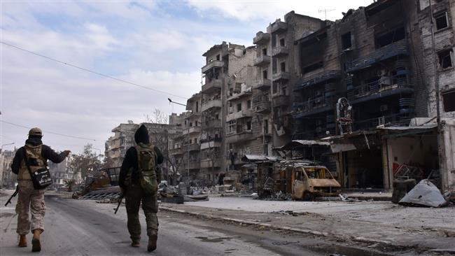 Syrian government forces walk past destroyed buildings in the former militant-held Ansari district in the city of Aleppo on December 23, 2016. (Photo by AFP)
