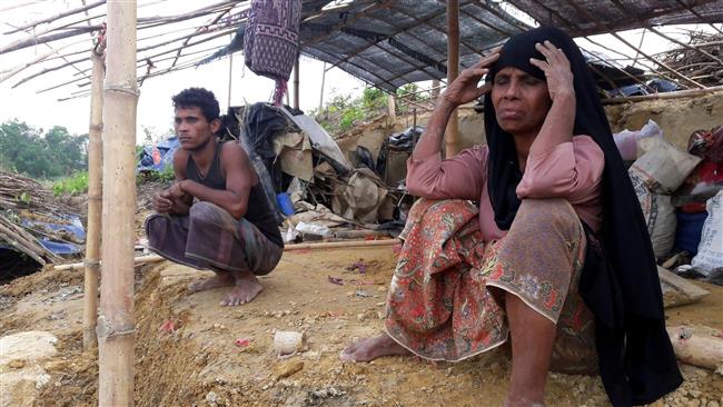 This file photo, taken on May 31, 2017, shows displaced Rohingya refugees from Myanmar sitting near a house destroyed by a cyclone at a squalid a camp in Bangladesh. (By AFP)
