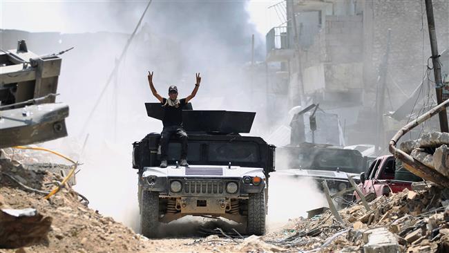 A member of the Counter-Terrorism Service (CTS) seated on the top of an advancing Humvee raises the victory gesture while advancing in the Old City of Mosul on June 30, 2017. (Photo by AFP)
