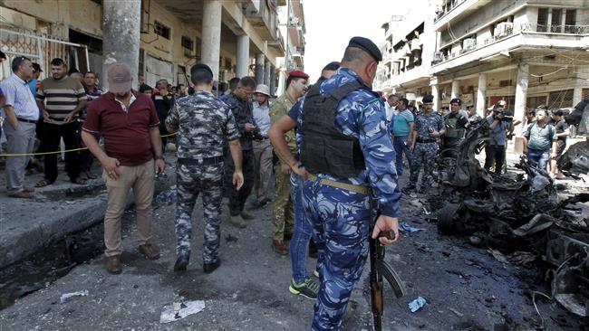 Iraqi civilians and security forces gather at the site of a car bomb explosion near Baghdad
