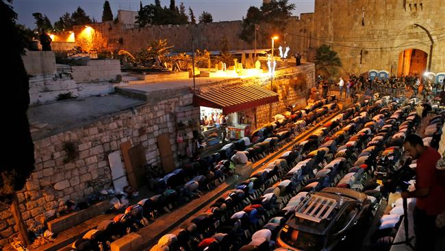 Palestinian Muslim worshipers pray next to Lions Gate, a main entrance to the al-Aqsa Mosque compound in Jerusalem al-Quds