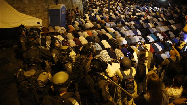 Israeli security forces stand by as Palestinian Muslim worshipers pray outside Lions