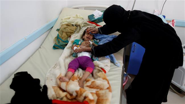 A woman helps her son as he lies on a bed at a cholera treatment center in Sana