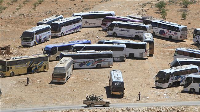 A military vehicle drives past parked buses that will transfer militants in the highlands of Arsal bordering with Syria on July 31, 2017. (Photo by Reuters)
