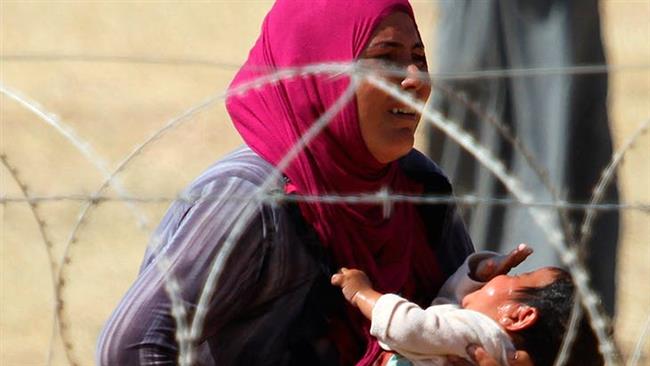 A Syrian mother and child, refugees from Raqqa, wait to cross into Turkey. (File photo)
