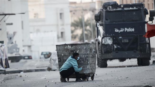 This AFP file photo taken on January 2, 2015 shows a Bahraini protester taking cover behind a garbage container during clashes with riot police following a demonstration on January 2, 2015.
