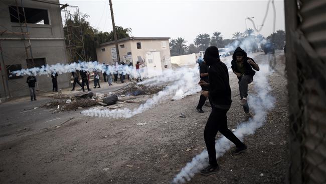This file photo taken on February 13, 2015 shows Bahraini protesters taking cover from tear gas during clashes with police in village of Bilad al-Qadeem on the outskirts of the capital Manama. (Photo by AFP)
