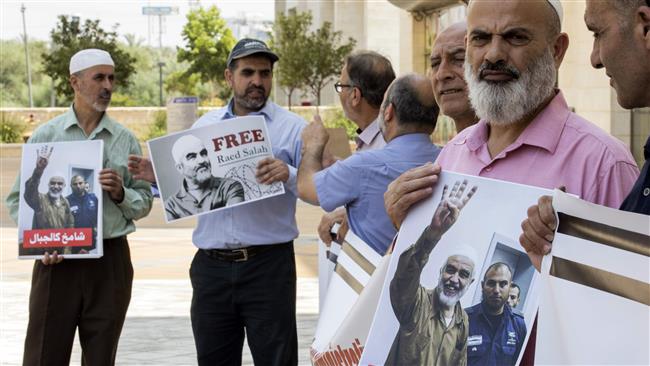 Supporters of Sheikh Raed Salah (portrait), the leader of the northern branch of the Islamic Movement in Israel, gather in protest against his arrest and detention, outside the Israeli Rishon Lezion magistrate court, near Tel Aviv, on August 17, 2017. (Photo by AFP)
