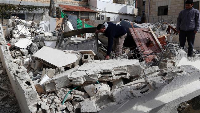 A Palestinian man gathers his belongings outside his house that was demolished by Israeli army bulldozers in occupied East Jerusalem al-Quds on February 22, 2017. (Photo by AFP)
