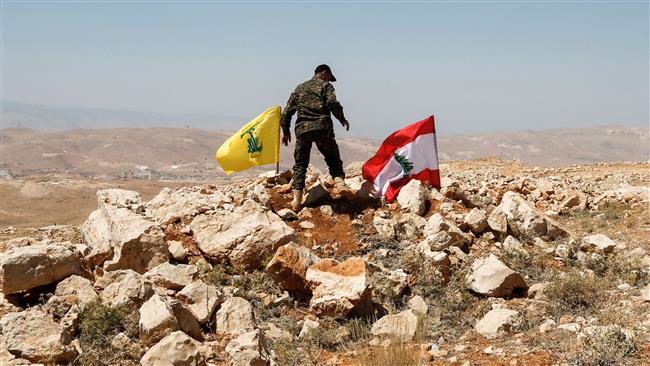 The picture, taken on July 26, 2017, shows a Hezbollah fighter placing a flag of the resistance movement and a Lebanese national flag in a mountainous area around the border town of Arsal. (By AFP)
