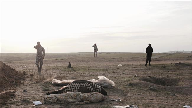 Iraqi forces stand at the site of a mass grave of Daesh victims in Mosul on March 15, 2017. (Photo by AP)
