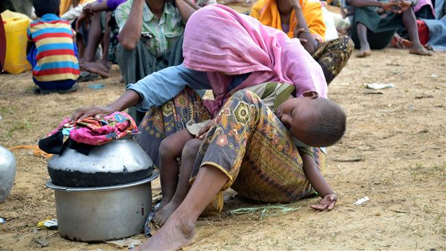 This August 29, 2017 photo shows an elderly Rohingya refugee while holding her sleeping grandson in her lap at the Kutupalong refugee camp after crossing the border from Myanmar into Bangladesh. (By AFP)
