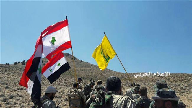 The photo released on Aug 28, 2017 shows Hezbollah fighters advancing up a hill as they hold Lebanese, Syrian and their group