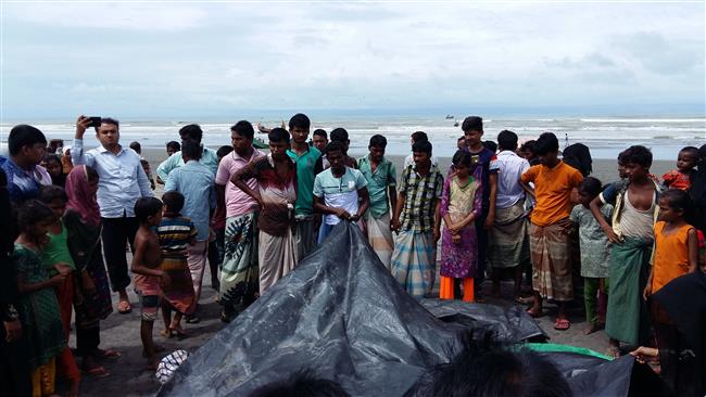 Bangladeshi onlookers watch on August 31, 2017 as a man covers the bodies of Rohingya women and children who drowned after their boat capsized on the Naf River near Teknaf. (Photo by AFP)
