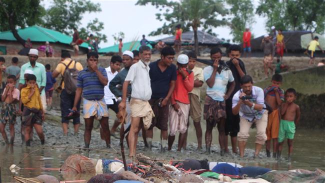 Bangladeshi onlookers stand next to dead bodies of Rohingya refugees washed up on the banks of the Naf river in Tenkaf on September 1, 2017. (Photo by AFP)
