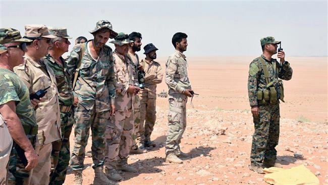 A Syrian soldier (R) speaks on a walkie-talkie as Syrian army troops and pro-government fighters stand next to him near the eastern city of Dayr al-Zawr, Syria, on September 4, 2017. (Photo by SANA)
