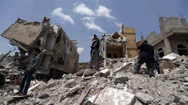 Yemeni men stand on the debris of a house hit in a Saudi airstrike on a residential district in the capital Sana