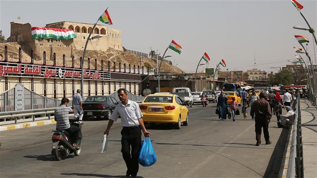 Iraqis walk past Kurdish flags in central Kirkuk on September 24, 2017, on the eve of the independence referendum for the Kurdistan region. (Photo by AFP)
