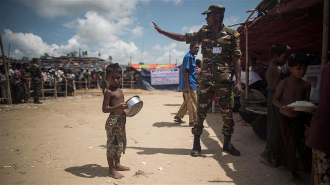A Bangladeshi soldier gestures as a Rohingya refugee child waits to receive his daily meal at a food distribution in Balukhali refugee camp near Gumdhum, October 1, 2017. (Photo by AFP)
