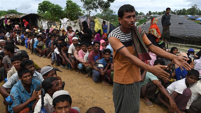 A volunteer urges Rohingya Muslim refugees to line up as they wait outside a food distribution center at the Kutupalong refugee camp in Bangladesh