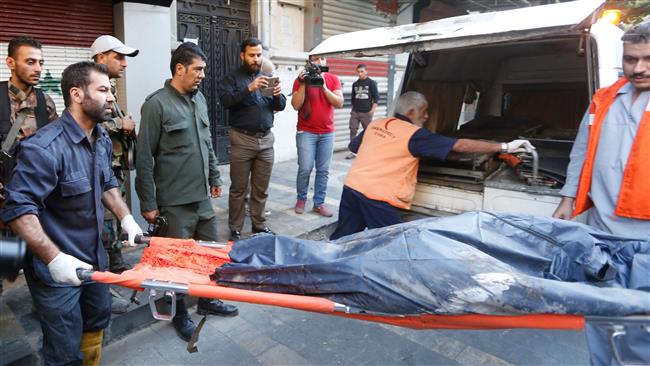 Syrian security forces carry the remains of a terrorist following an attack near the main police headquarters in Syria