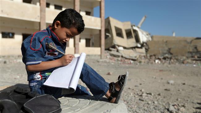 A Yemeni schoolboy writes as he sits outside a school that was damaged in an airstrike by Saudi warplanes in the southern Yemeni city of Ta