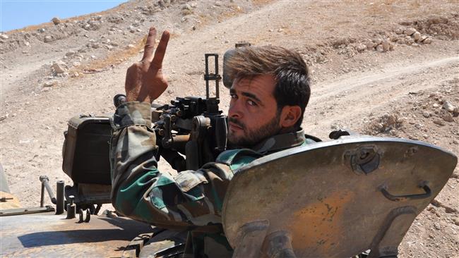 A member of the Syrian government forces gestures to the camera from a tank in the Salamiyah city, some 33 kilometers southeast of Hama, on August 19, 2017, during an offensive against Daesh. (Photo by AFP)
