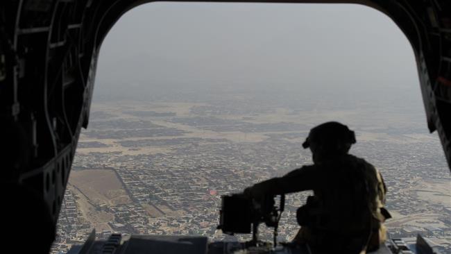 In this photograph, taken on August 10, 2017, a US soldier sits in the rear of a Chinook helicopter while flying over Kabul, in Afghanistan. (By AFP)