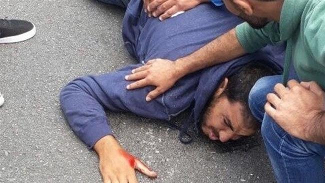 A Palestinian youth lies on the ground near the Israeli settlement of Halamish to the north of the city of Ramallah in the occupied West Bank on October 31, 2017 after his vehicle is shot by Israeli forces. (Photo by Ma’an News Agency)
