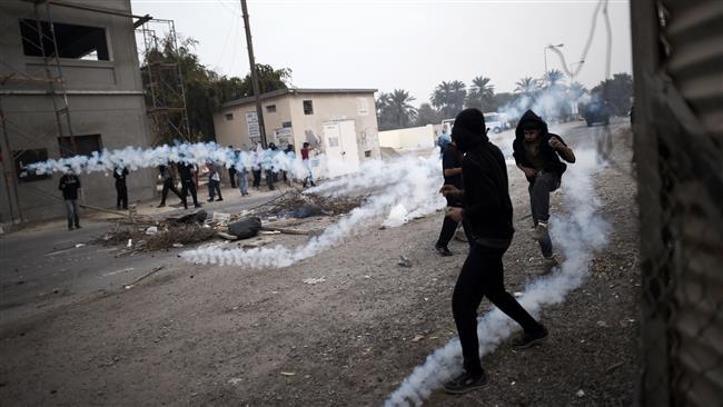 The photo taken on February 13, 2015 shows Bahraini protesters taking cover from tear gas during clashes with regime forces on the outskirts of the capital Manama. (Photo by AFP)
