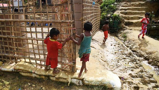 Young Rohingya Muslim refugees walk back to their temporary makeshift shelters at the Moynar Ghona refugee camp in the Bangladeshi district of Ukhia on November 1, 2017. (Photo by AFP)
