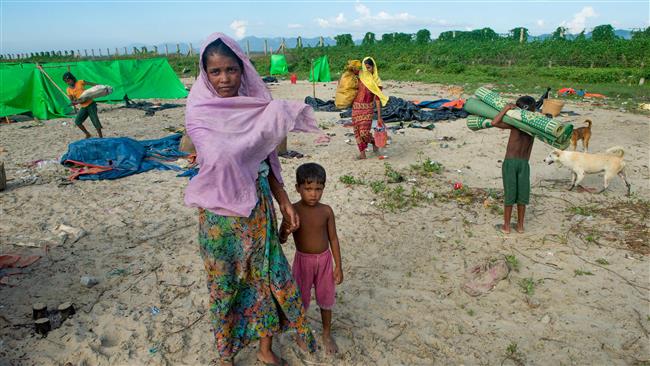 In this photograph taken on November 12, 2017, a woman holds the hand of a child as they stand near tents at a makeshift camp in Rakhine state in Myanmar, while waiting to find a way to cross over into Bangladesh. (Photo by AFP)
