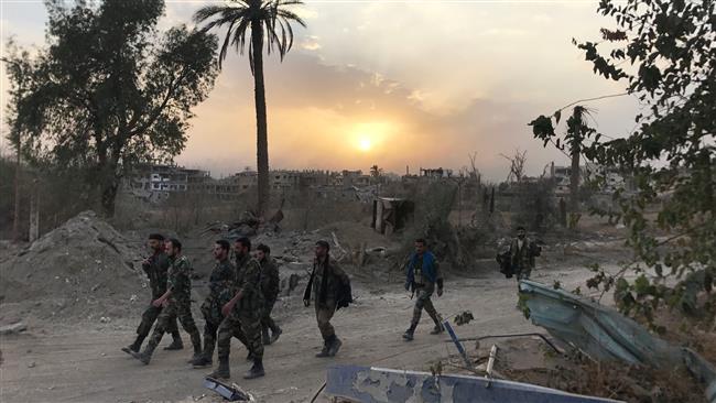 Syrian government forces walk through a road in a northeastern district of Dayr al-Zawr on November 5, 2017, after retaking the city from Daesh Takfiri terrorists. (Photo by AFP)
