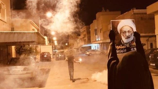 This photo taken from social media shows a Bahraini protester holding a picture of prominent Shia figure Sheikh Isa Qassim during an anti-regime protest.
