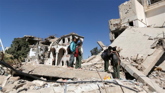 Boys stand on the wreckage of a building hit by Saudi airstrikes two years ago in Sana