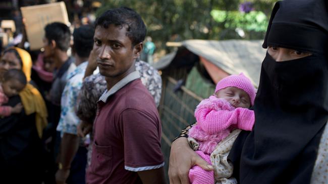 A Rohingya Muslim woman, who crossed over from Myanmar into Bangladesh, carries her newborn baby and waits to collect aid at the Kutupalong refugee camp in Ukhiya, Bangladesh, on December 21, 2017. (Photo by AP)
