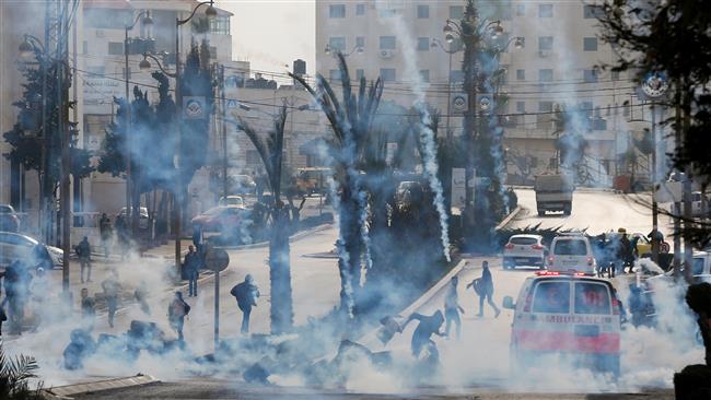 Palestinian protesters take cover from tear gas during clashes with Israeli forces north of Ramallah on January 12, 2018. (Photo by AFP)
