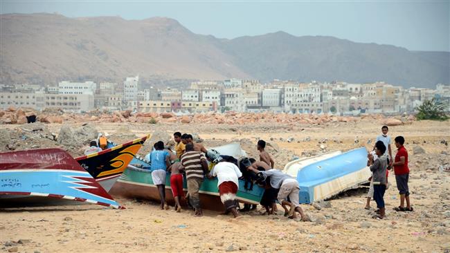 Yemeni fishermen push a boat to shore in the southern city of Mukalla in Yemen