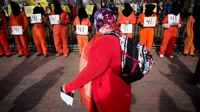 A woman walks past activists protesting the Guantanamo Bay detention camp during a rally in Lafayette Square outside the White House January 11, 2018 in Washington, DC. (Photo by AFP)
