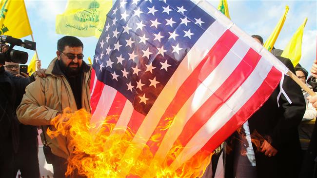 Lebanese supporters of the Hezbollah resistance movement burn a US flag during a rally against the US president