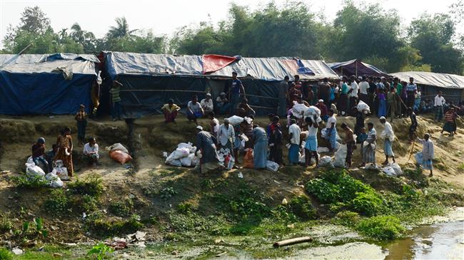 Rohingya refugees collect relief material next to a settlement near the no-man