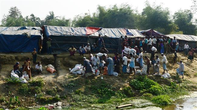 Rohingya refugees collect relief material next to a settlement near the no man’s land area between Myanmar and Bangladesh. (File photo by AFP)
