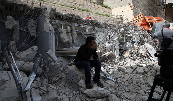 Palestinian man sits on the ruins of his house destructed by Israeli forces