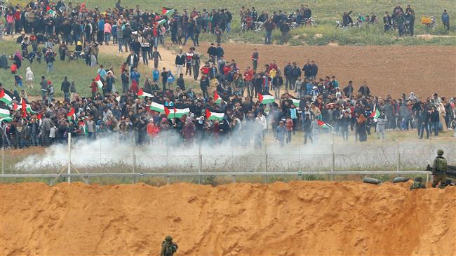 A picture taken on March 30, 2018 from the southern Israeli kibbutz of Nahal Oz across the border from the Gaza Strip shows Palestinians participating in a tent city protest commemorating Land Day, with Israeli soldiers seen below in the foreground. (Photo by AFP)
