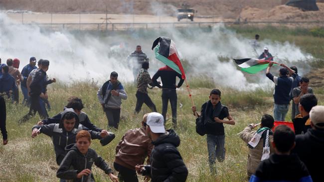 Palestinians run for cover from tear gas fired by Israeli forces during clashes following a demonstration commemorating Land Day in the Gaza Strip on March 30, 2018. (Photo by AFP)
